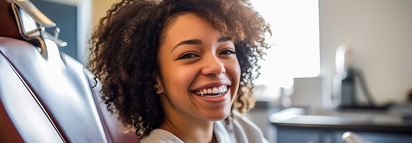 A woman sitting in a dentist's chair with a smile on her face