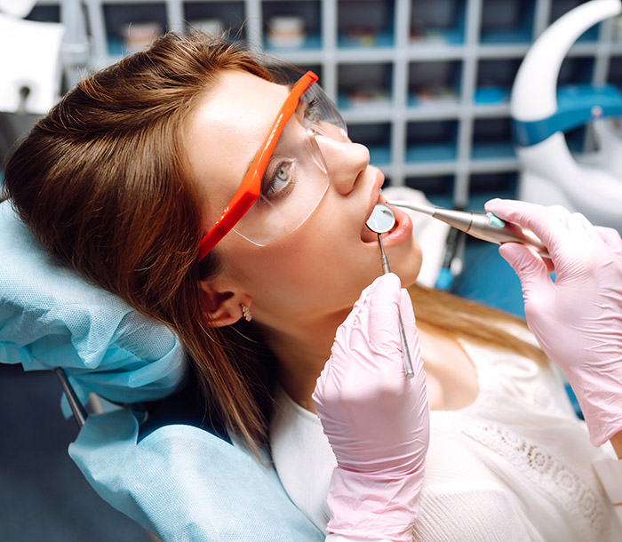 Young woman opening her mouth wide during treating her teeth by